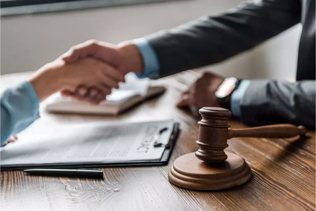 Focus on Lady of Justice with lawyer helping client sign contract in background